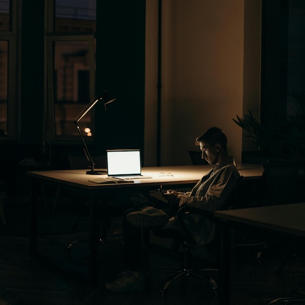 A man working late in the dark by a computer